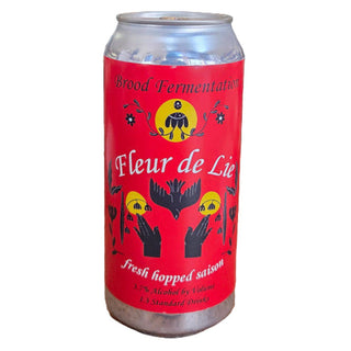 Can of 'Fleur de Lys' beer on a wooden table with a bar setting in the background.