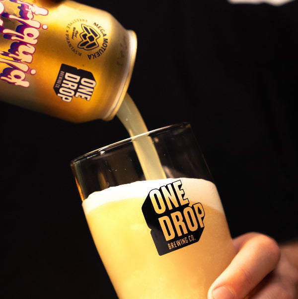A can of One Drop Brewing beer being poured into a glass, with a visible logo and the words 'One Drop Brewing' on the can.